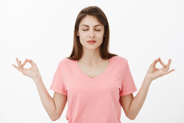 Calm and relieved attractive brunette woman posing in the studio