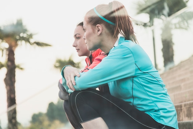 Calm sportswomen sitting on stairs