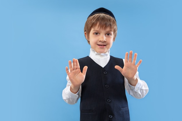 落ち着いて、やめて。青い壁に隔離された若い正統派ユダヤ人の少年の肖像画。プリム、ビジネス、お祭り、休日、子供時代、お祝いのペサッハまたは過越の祭り、ユダヤ教、宗教の概念。