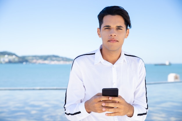 Calm young man using smartphone