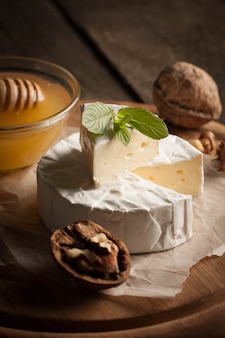 Сыр камамбер и бри на деревянной предпосылке с томатами, салатом и чесноком. итальянская еда. молочные продукты.
