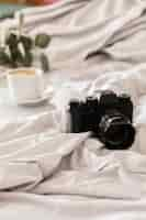 Free photo camera on bed and coffee cup