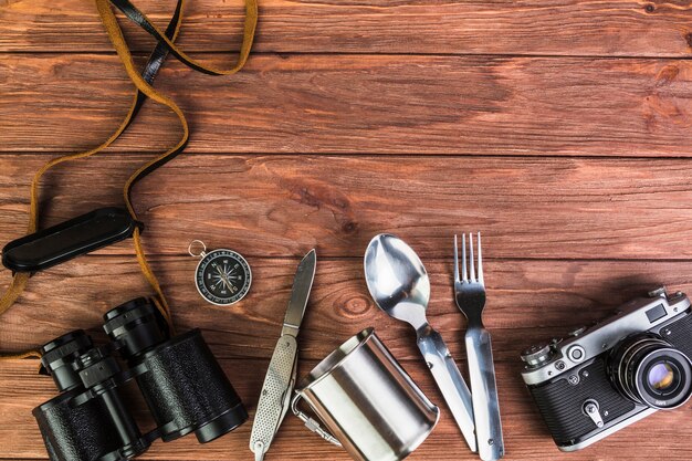 Camera and binocular with kitchen utensils on wooden table