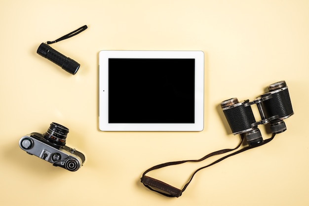 Free photo camera; flashlight; binocular and digital tablet on beige background