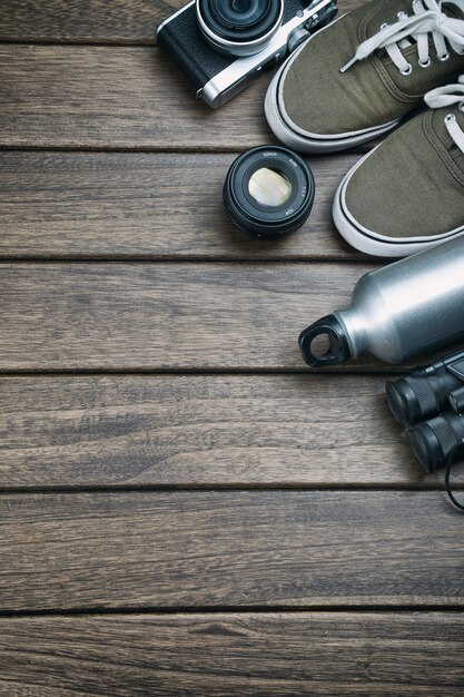 Камера, объектив, бинокль, холст обувь, спортивная бутылка на ретро деревянный стол