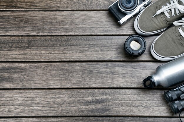 Camera, lens, binocular, canvas shoes, sports bottle on the retro wooden table