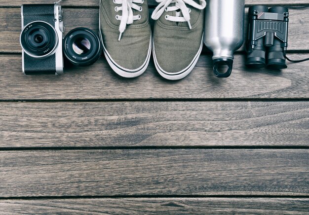 Camera, lens, binocular, canvas shoes, sports bottle on the retro wooden table