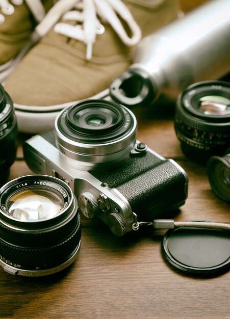 Camera, lens, binocular, canvas shoes, sports bottle on the retro wooden table