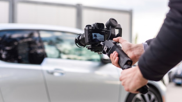 Человек камеры со стабилизатором съемки припаркованный BMW i3