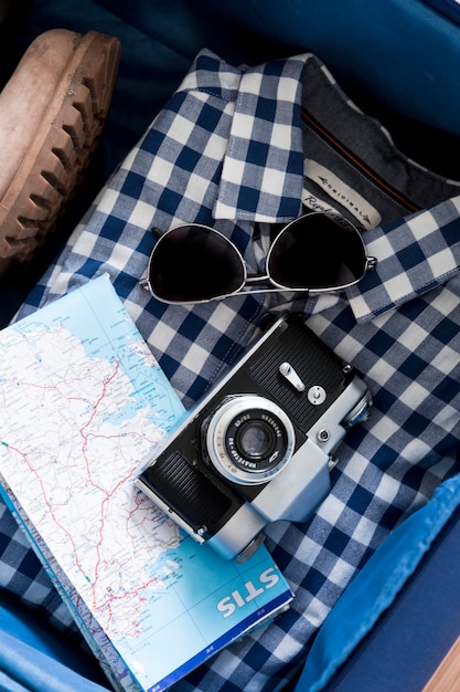 Free photo camera and map on shirt in suitcase