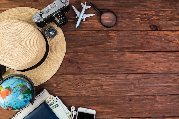 Camera, mobile, globe, straw hat and compass on wooden plank