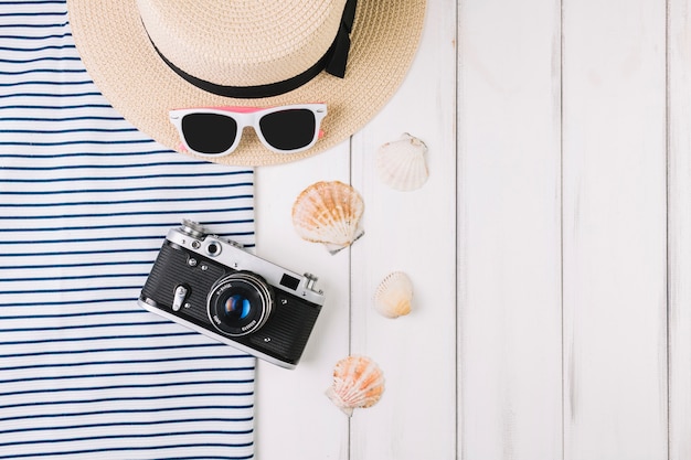 Camera and seashells near hat and sunglasses