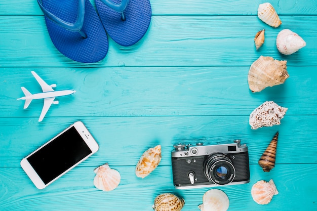 Camera and smartphone near seashells and flip-flops