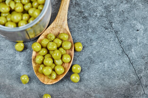 A can of boiled green peas and a wooden spoon.