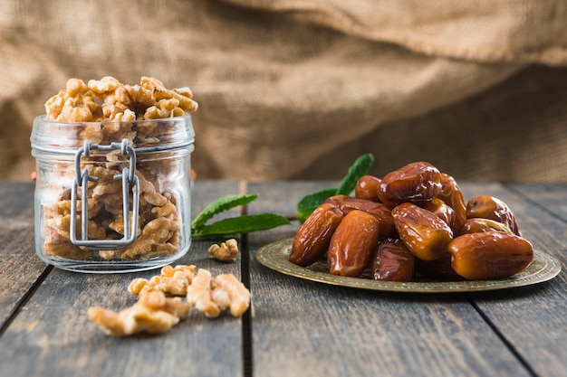 Can with nuts near plant twig and dried fruits on table