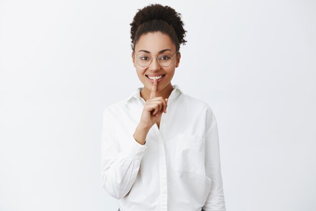 Can you keep secrets. Joyful thrilled african-american female woman doing silence gesture