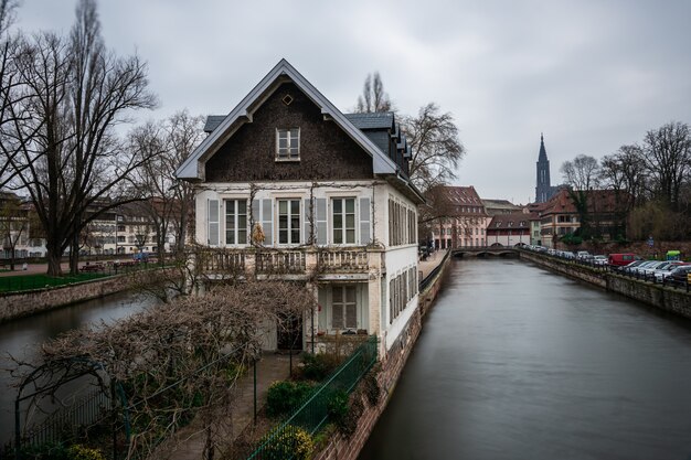 Canal surrounded by buildings and greenery under a cloudy sky in Strasbourg in France