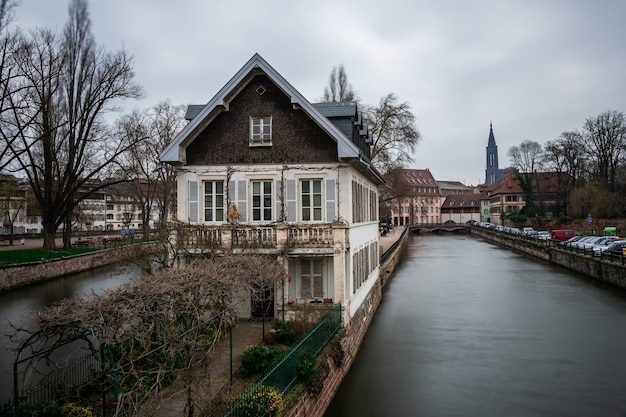 Canal surrounded by buildings and greenery under a cloudy sky in Strasbourg in France