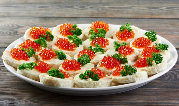 Canapees with butter,red caviar and parsley, served for restaurant catering or buffet. Good for light alcohol drinksand other meals.