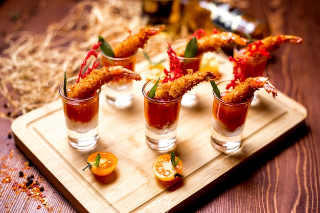 Canapes in shots with fried prawns in tomato sauce side view