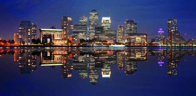 Canary Wharf business district in London at night over Thames River.