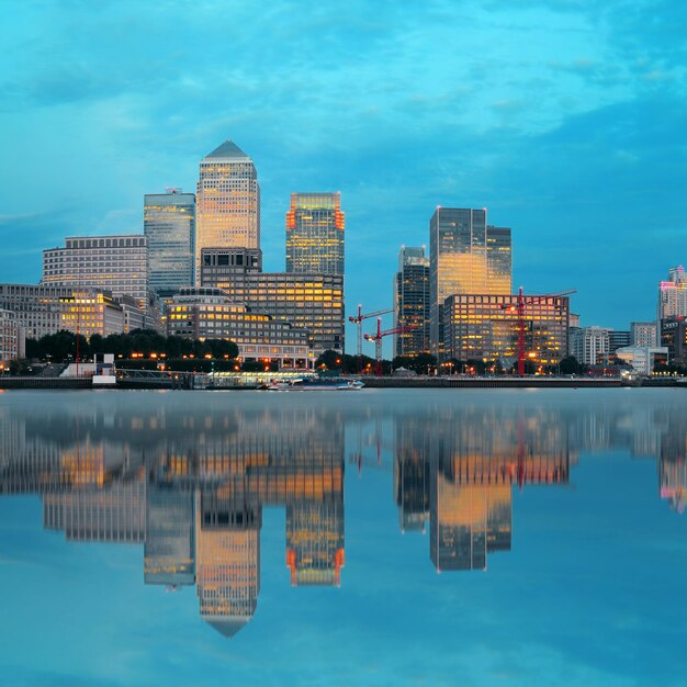 Canary Wharf business district in London at sunset with reflection.