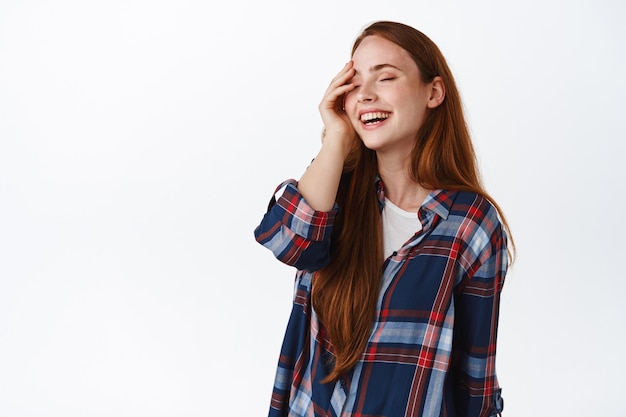 Candid happy redhead girl, laughing and smiling white teeth standing on white.