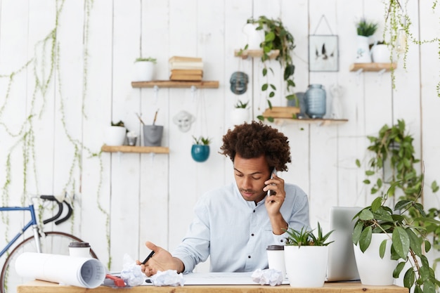 Free photo candid indoor shot of serious african american engineer having phone conversation