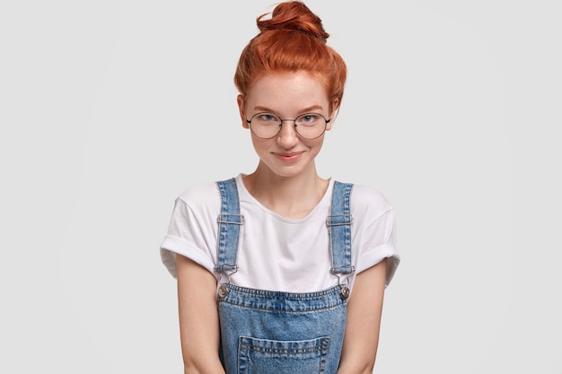 Candid shot of pleasant looking female with ginger hair bun