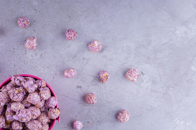 Candied popcron inside and scattered around a small bucket on marble background. High quality photo