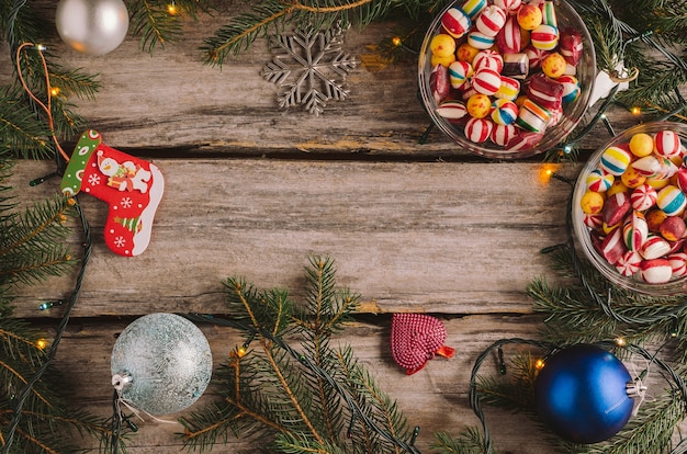 Candies, Christmas baubles and spruce tree branches on a wooden surface