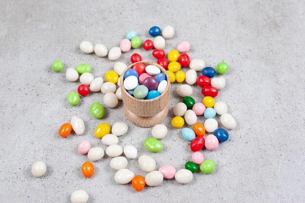 Candies filled into a tiny bowl and scattered around on marble surface