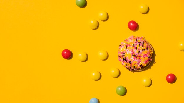 Candies with sprinkle donut on yellow background