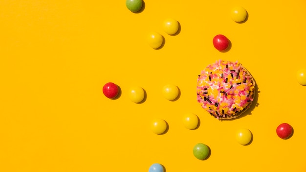 Candies with sprinkle donut on yellow background