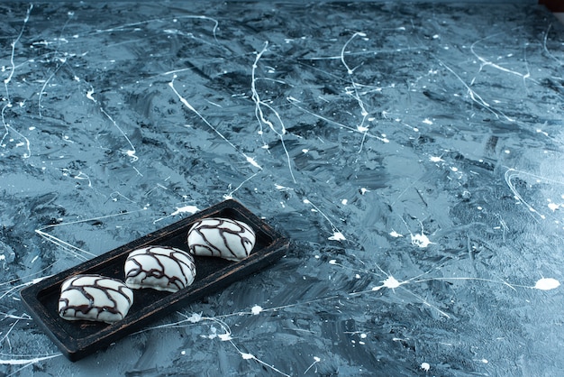 Candies on a wooden plate , on the blue table. 