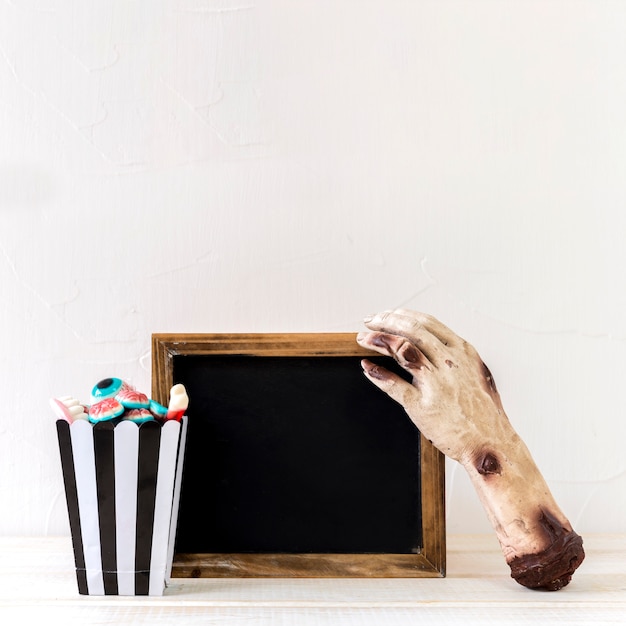 Candies and zombie hand near chalkboard