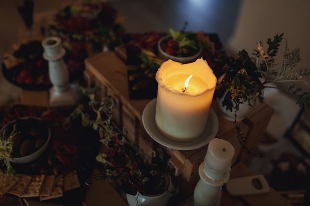 Candle burns on a table with snacks