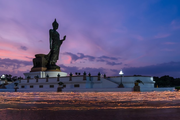 Phuttha Monthon 불교 공원 Nakhon Pathom Thailand에서 Vesak day 또는 Buddha Birthday에 황혼의 부처님 동상 주변의 촛불 행렬 의식