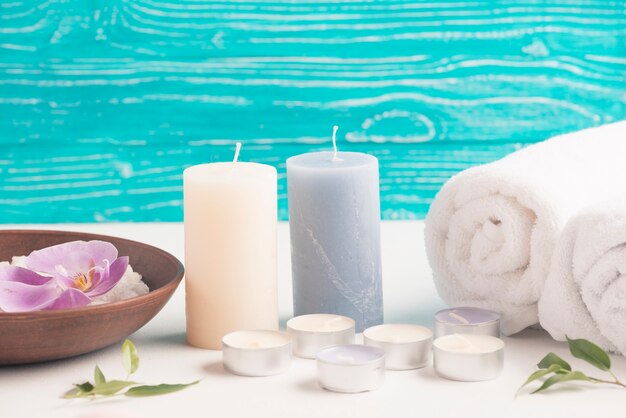 Candle with rolled up towel and spa slat with orchid flower on desk