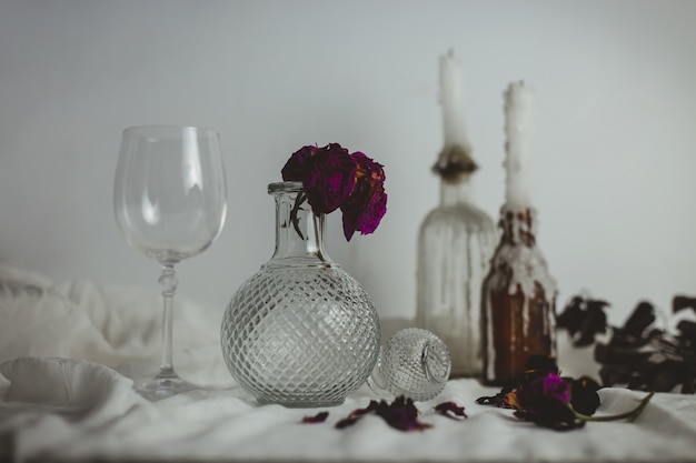 Free photo candles on the bottles next to a vase with a flower inside and a glass