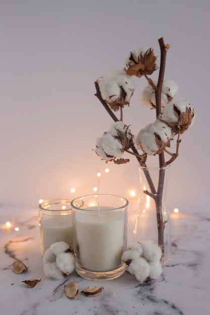 Candles decorated with cotton twig and lighting equipments on marble surface