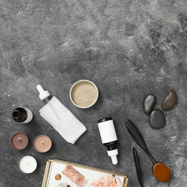 Свечи; бутылка эфирного масла; глина rhassoul; последний; гималайская каменная соль на подносе на черном бетонном фоне