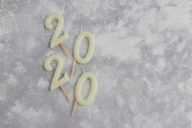 無料写真 クリスマスの横にある新年のシンボルとしての数字2020の形のキャンドルは、灰色のテーブルに輝くキャンディーの形をしています。平面図、平置き