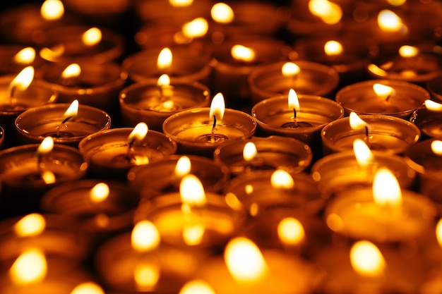 Candles. Many burning candles in dark. Yellow candles on black background.