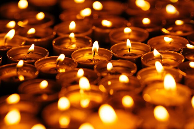 Свечи. Многие горят свечами в темноте. Желтые свечи на черном фоне.