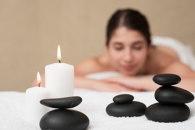 Candles and spa rocks with woman at spa