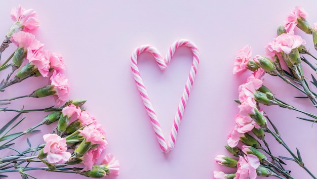 Candy canes in heart shape with flowers on table 