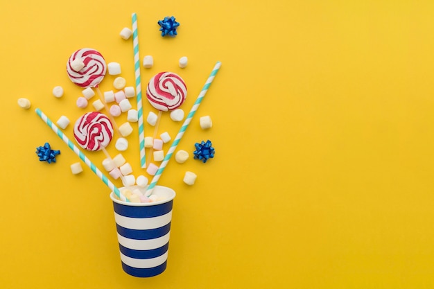 Candy and paper cup on yellow background