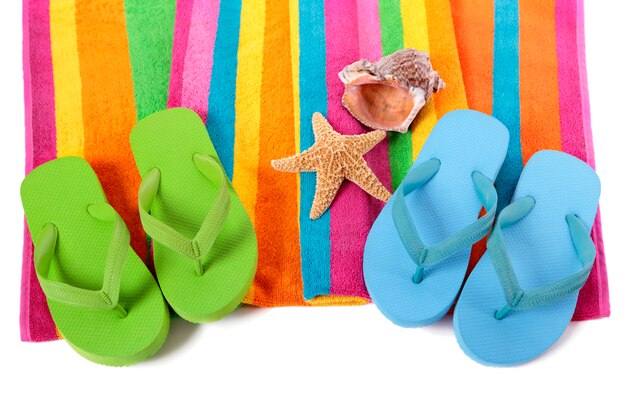 Free photo candy stripe beach towel with flip flops, starfish and seashell isolated on white.