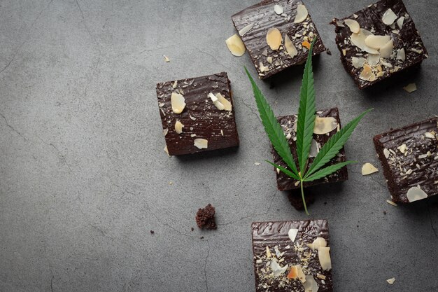 Cannabis brownies and cannabis leaves put on dark floor